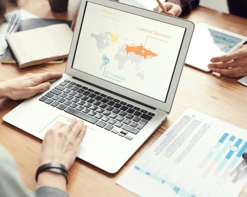 Professional team discussing global marketing strategies with charts and graphs on a laptop.