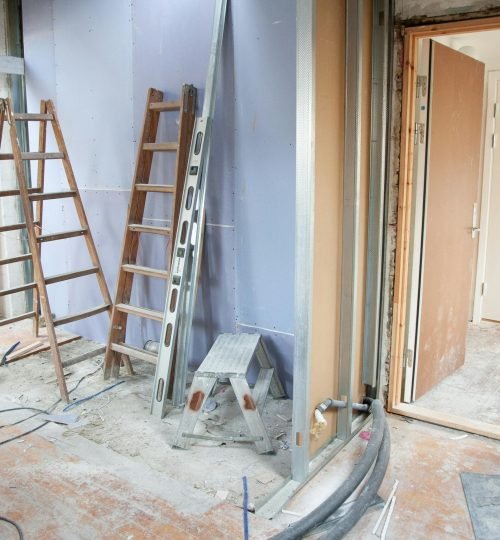 Construction site featuring ladders and tools in a home renovation setting.